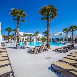Piscina con palme e lettini in un resort moderno.