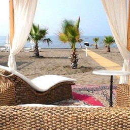 Letto balinese sulla spiaggia con palme sullo sfondo.