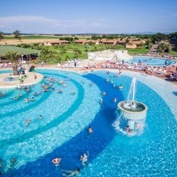 Piscina grande con fontana e molte persone che si divertono.