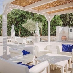 Area lounge all'aperto con divani bianchi e cuscini blu.