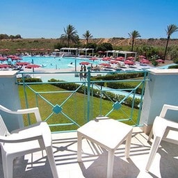 Balcone con tavolo vista piscina e giardino in un resort.